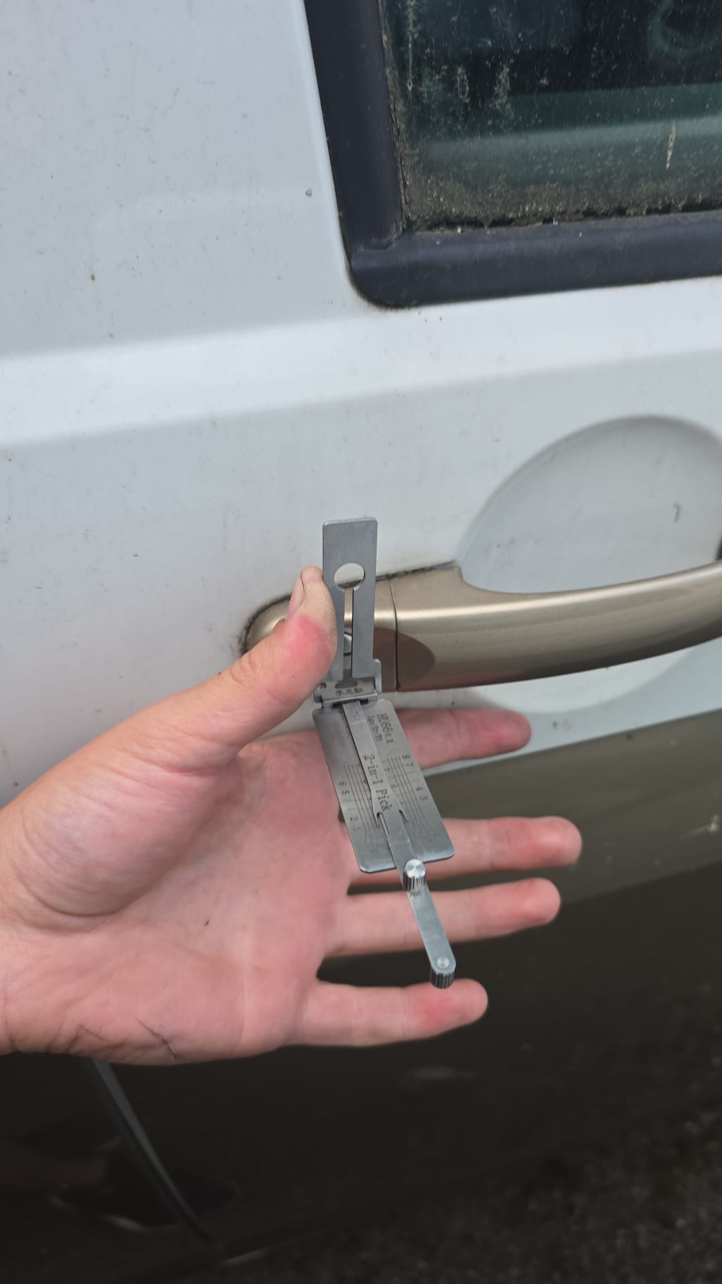 Two-in-one lock pick tool held at a van door handle during a non-destructive vehicle unlock